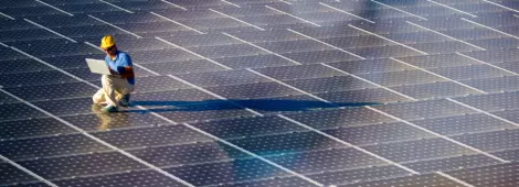 Image of a engineer with a laptop at a photovoltaic farm.