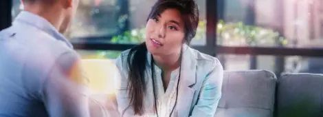 While sitting in a comfortable waiting room, female doctor listens to her patient.
