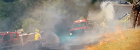 Firefighters working a natural cover fire in grass using brush truck apparatus