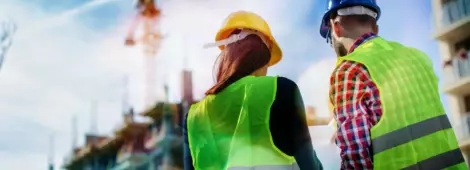 Two construction workers wearing protective gear discussing next steps