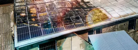 Aerial view of ruined building on fire with collapsed roof and rising dark smoke