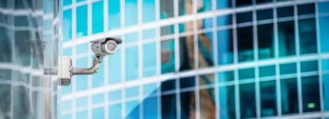 Security Camera on office building, reflecting in building behind it.