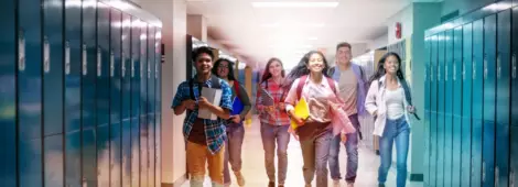 Cheerful male and female students running in illuminated corridor.