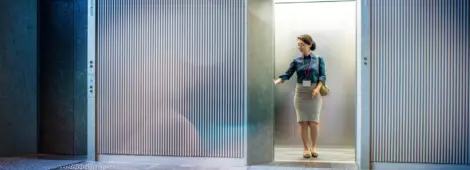 Asian businesswoman standing in elevator, waiting for doors to close.