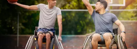 Tow young men in wheelchair playing basketball on court