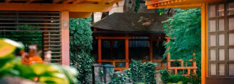 Outdoor garden at Japanese-style restaurant, landscaped design with bushes and red building