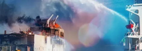 Burning ship and fire fighting boat sprays jets of water