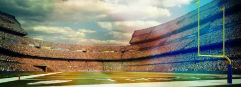 A panoramic image of a outdoor American football stadium full of spectators under blue sky.
