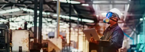 Man with protective mask and computer laptops in factory is investigating a chemical plant.