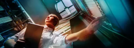 Young engineer businesswoman in network server room.