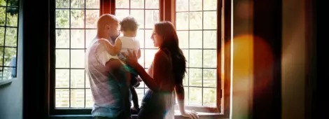 Shot of a young family looking out of the window in their new home