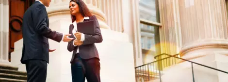 Professional woman and man having a discussion on the stairs of a stately building.