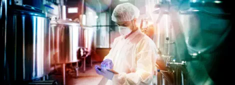 Professional technologist using tablet in production plant checking productivity and quality.