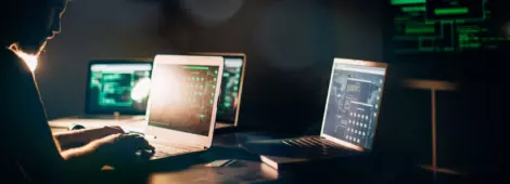 One hacker sitting in the dark room in front of his computers, hacking some internet data.