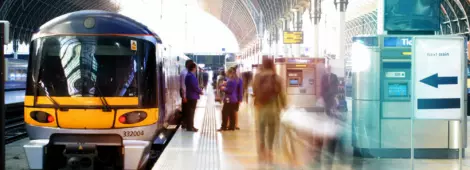A train at a train station. Blurred station staff and commuters on the platform.