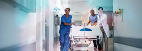 Full length shot of a medical team pushing a patient down the hallway in a gurney