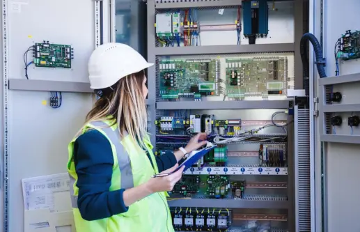 woman service engineer wearing white hard hat ,conducts a safety check front of a control panel