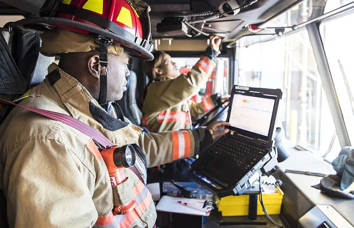 a female firefighter in the drivers seat of a fire engine, a male firefighter in the passengers seat