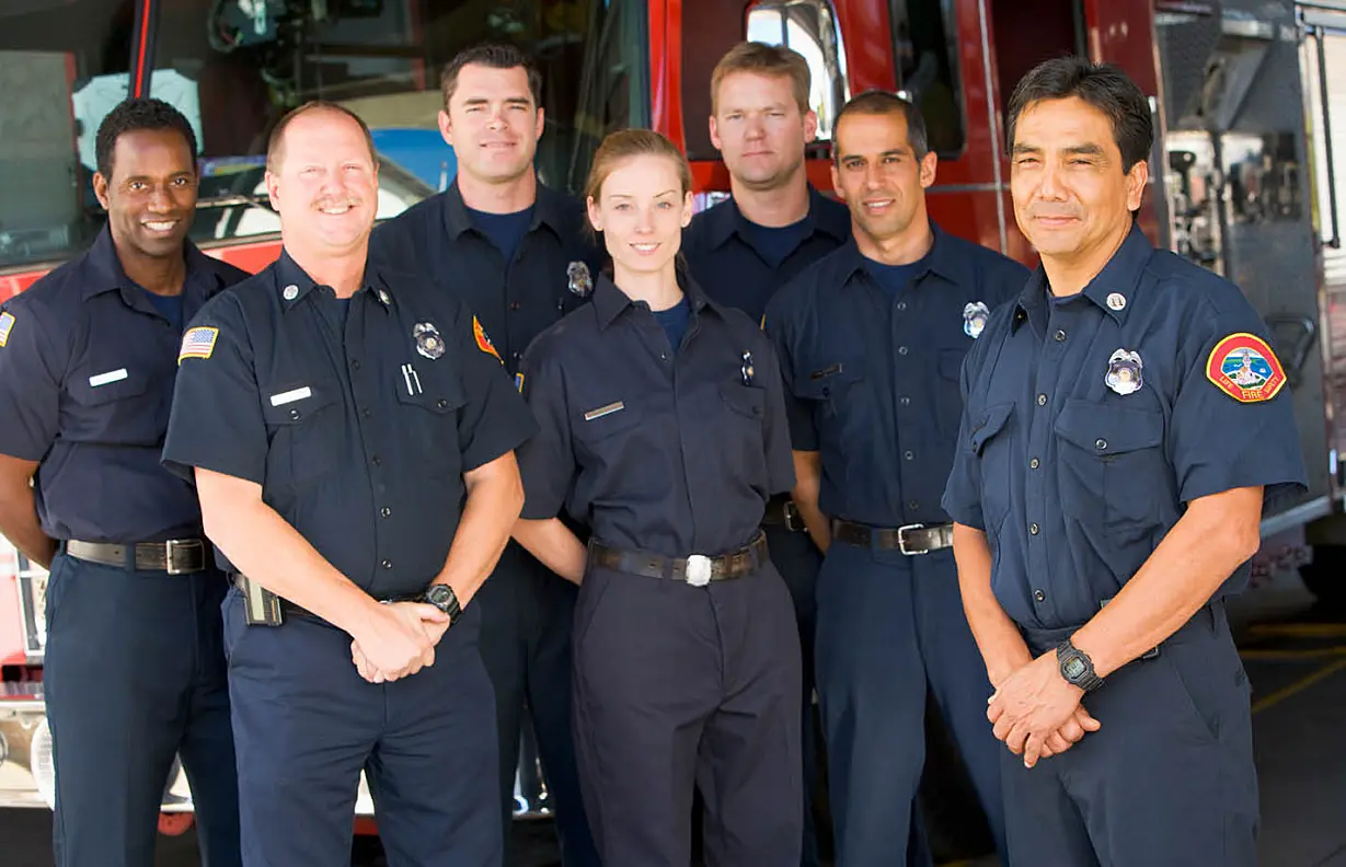 Six firefighters standing in front of fire engine with captain