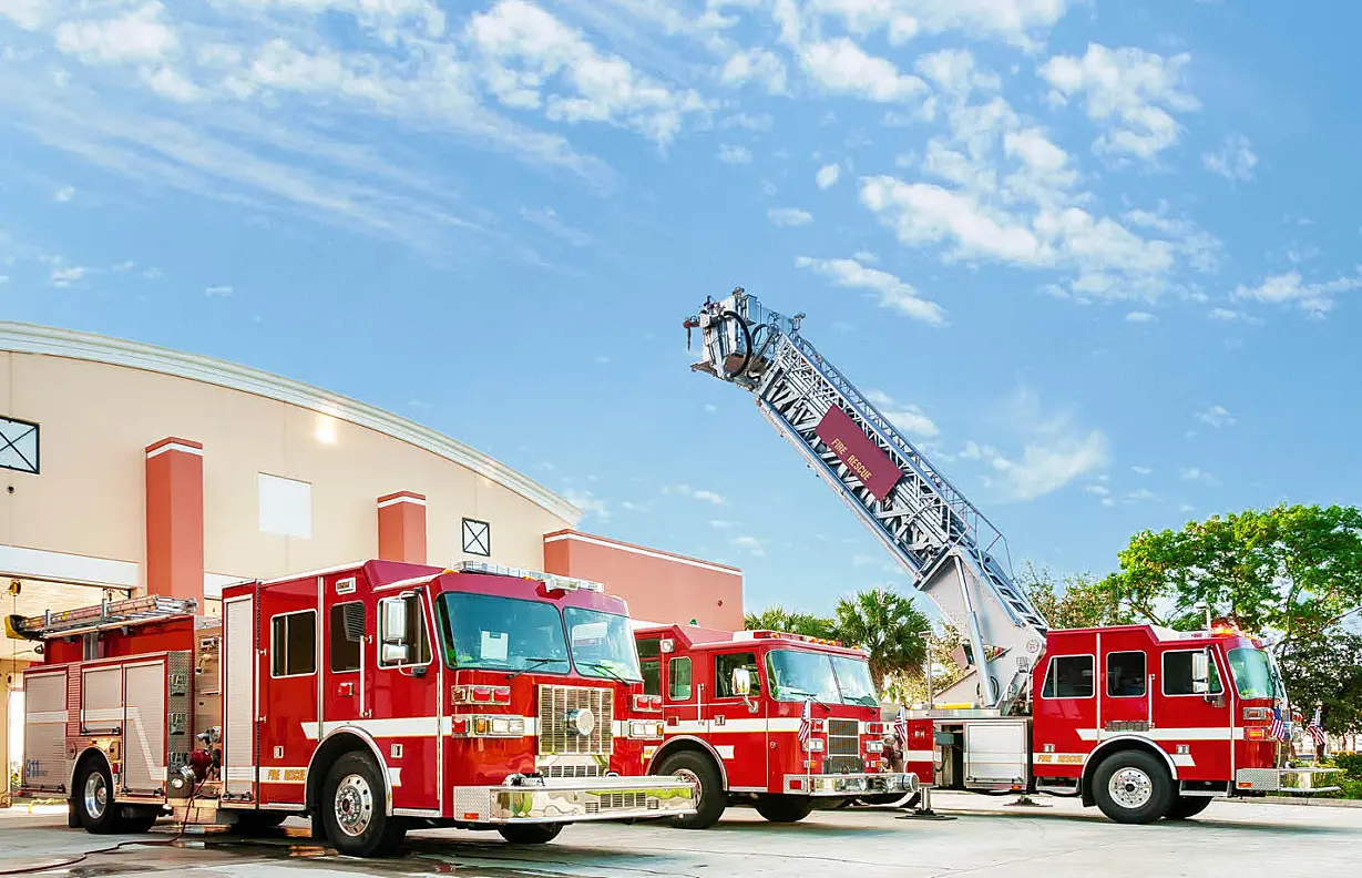 three red fire trucks parked in front of the fire station
