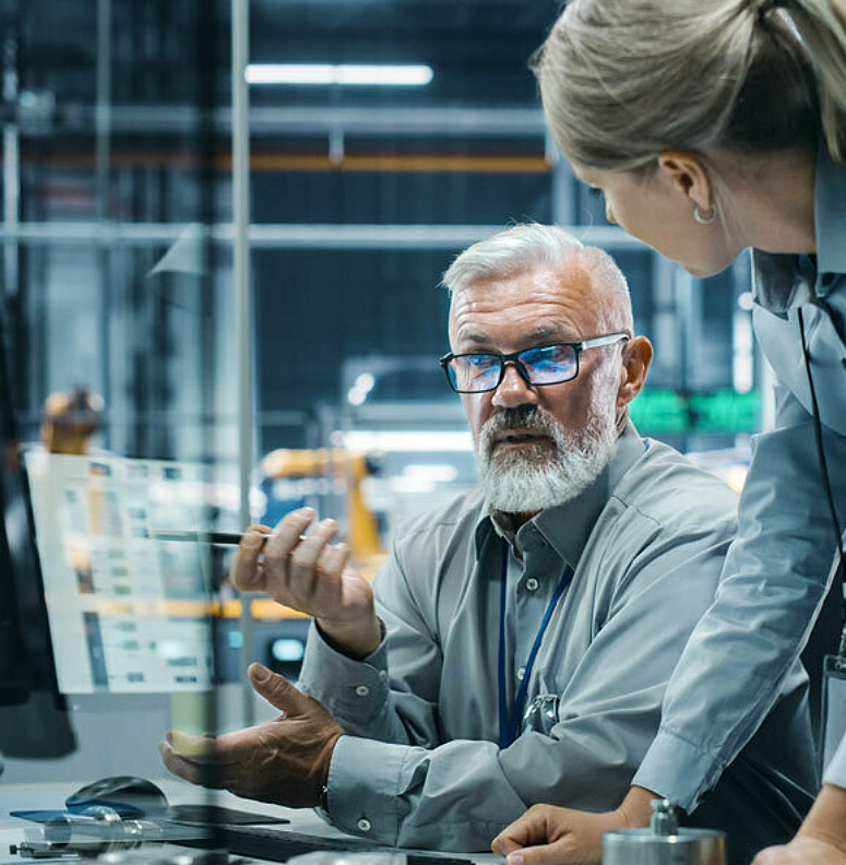 Man and woman in manufacturing environment looking at computer