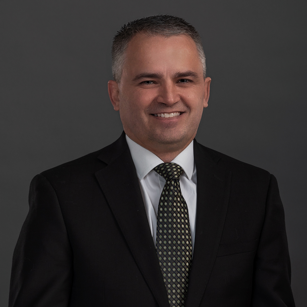 Executive headshot of a man in a dark suit