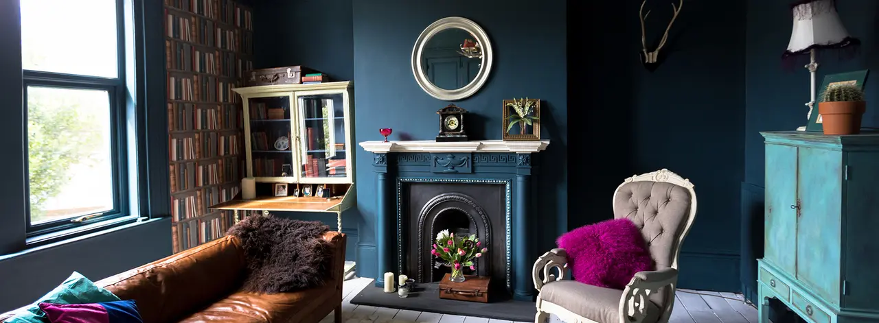 Dark blue living room with a leather sofa, cast-iron fireplace and eclectic vintage furniture
