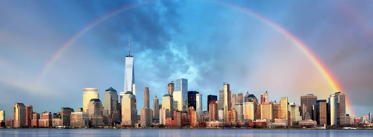 Lower Manhattan skyline under a full rainbow, seen across the Hudson River