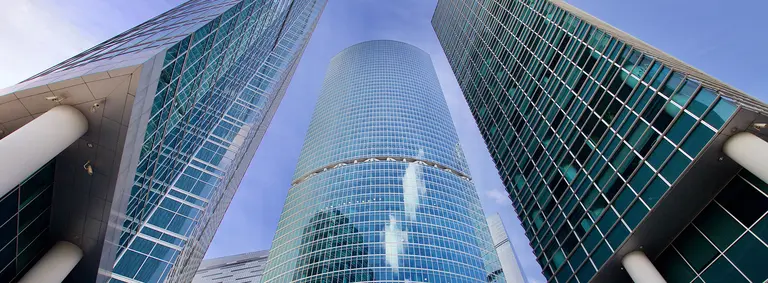Looking up at glass-clad commercial office towers against a blue sky