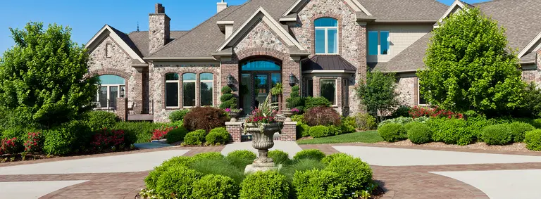 Stone and brick suburban home with a circular driveway and manicured landscaping