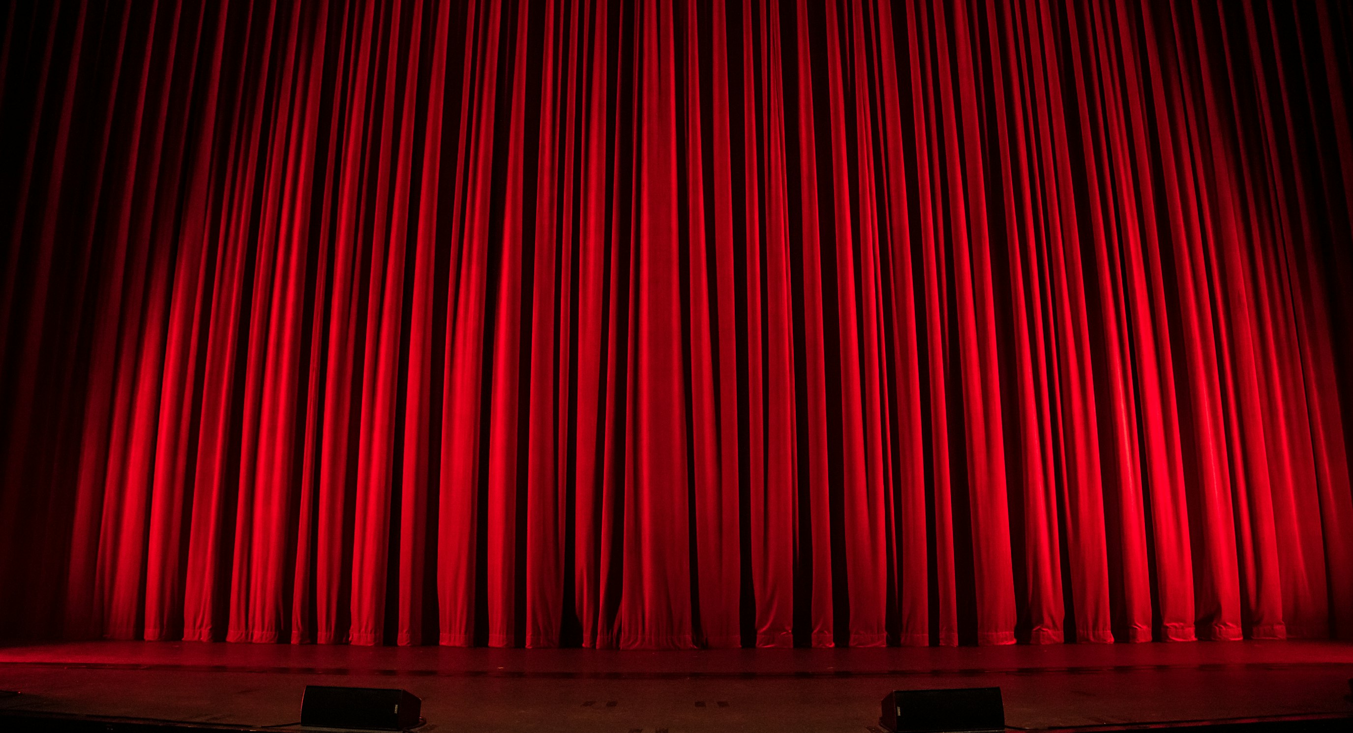 Red theater stage curtain under stage lighting