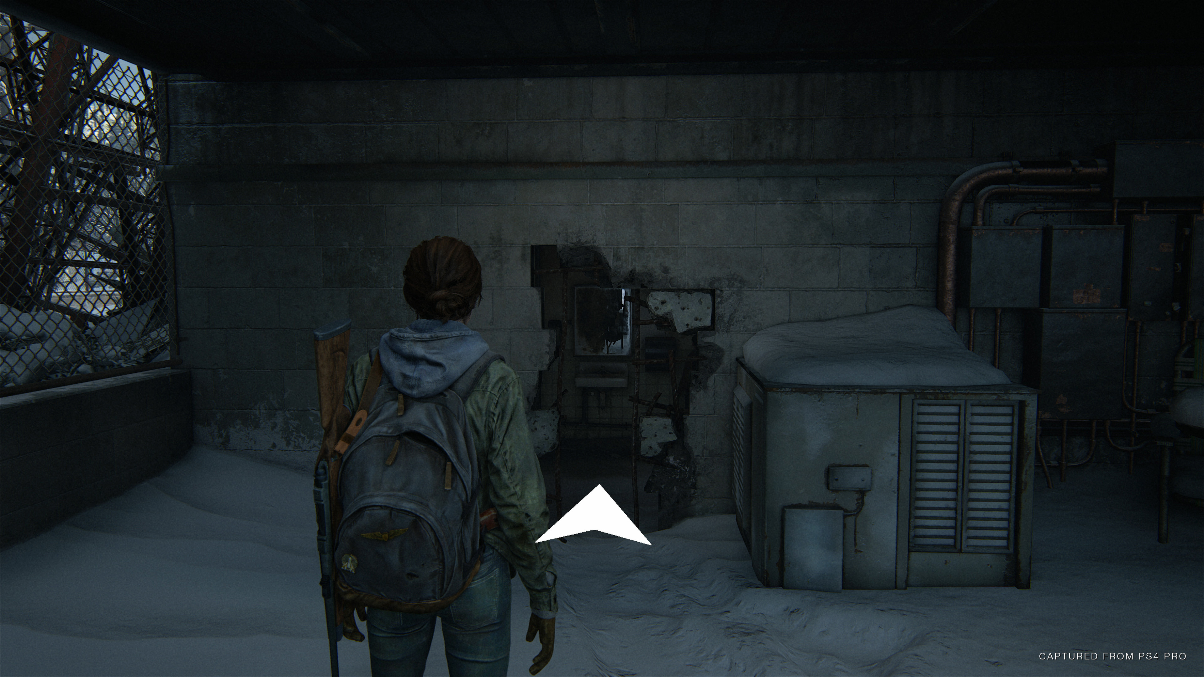 The player in front of a large hole in the wall, with a navigation assistance arrow pointing towards it