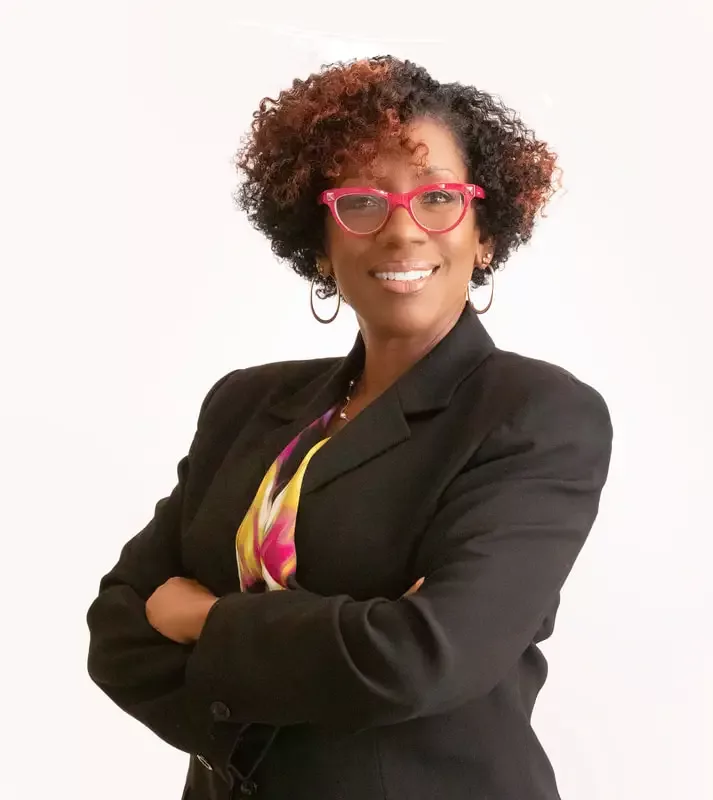 Portrait of Shondra Summers-Armstrong with her arms crossed, smiling, with glasses on