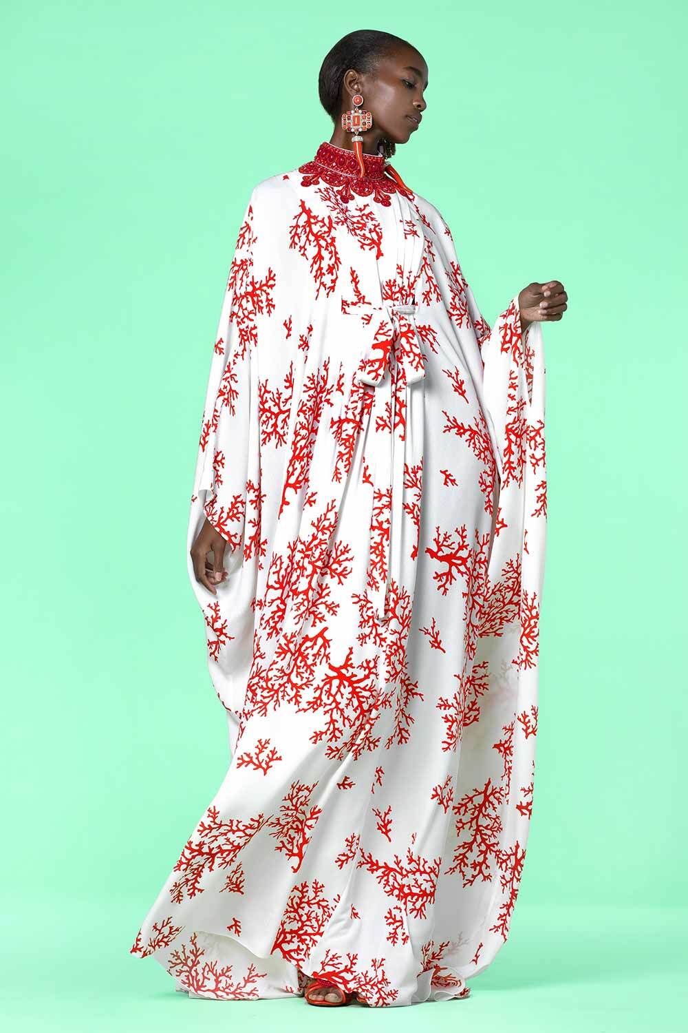 A model poses in a caftan with coral-like jewelry.