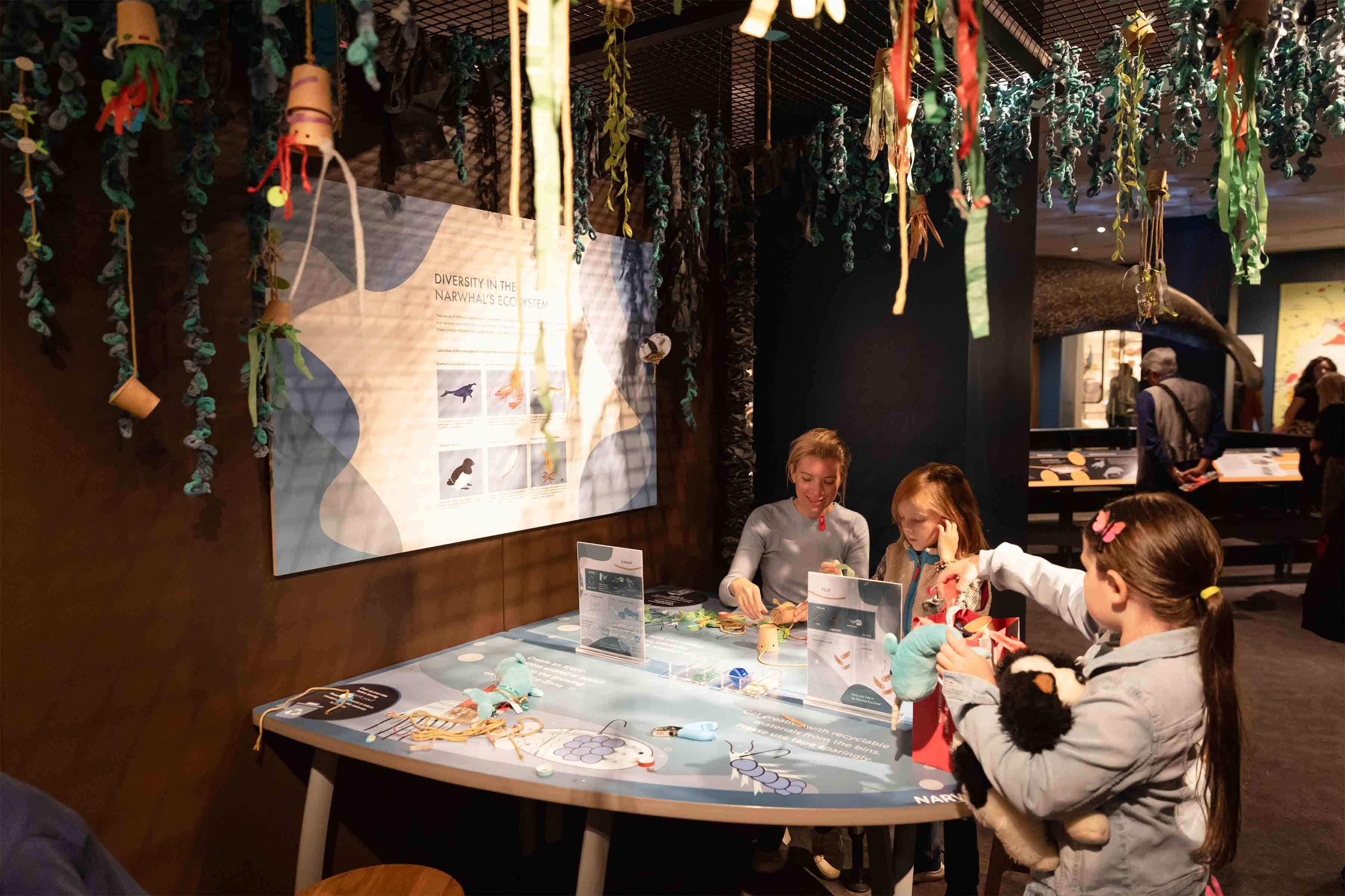 Family sitting at the interactive table in Narwhal: Revealing an Arctic Legend exhibition