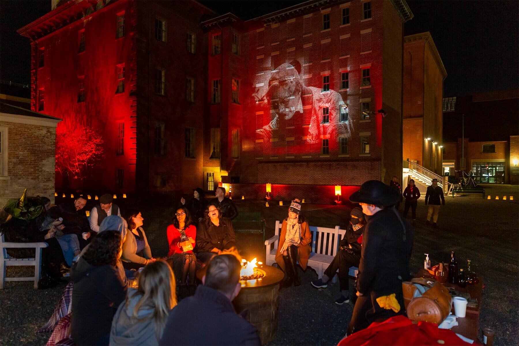 Nighttime gathering with attendees seated in front of a red-lit brick building showing a projected image from the film Nosferatu