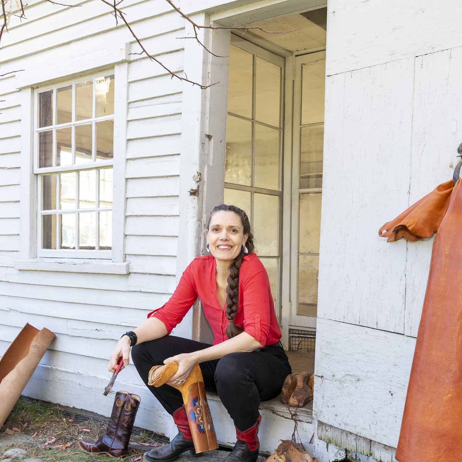 Sarah Guerin sitting on the doorstep to Tapley-Lye Ten Footer Shoe Shop