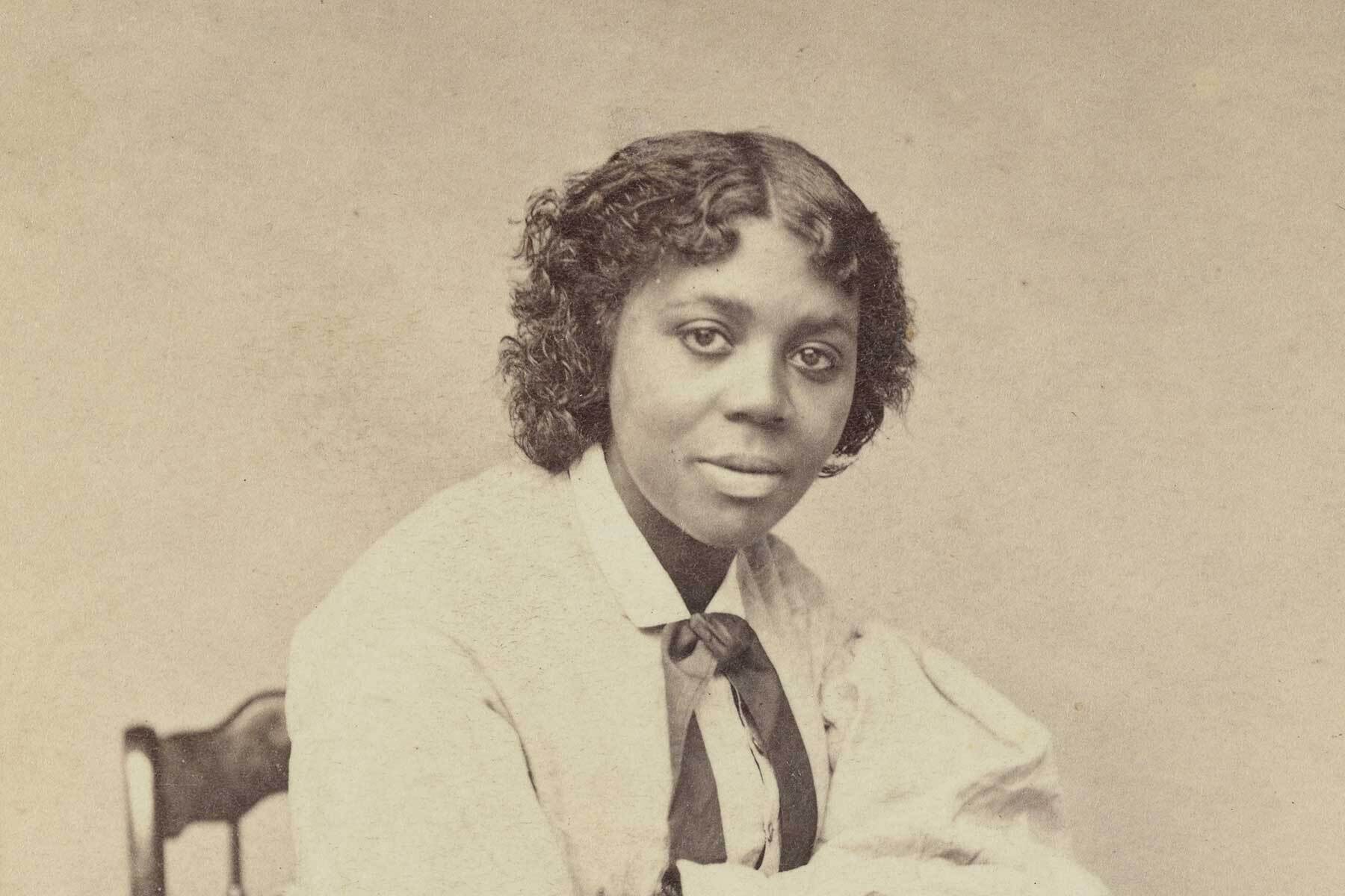 Edmonia Lewis photographed sitting at a table wearing a long sleeved shirt