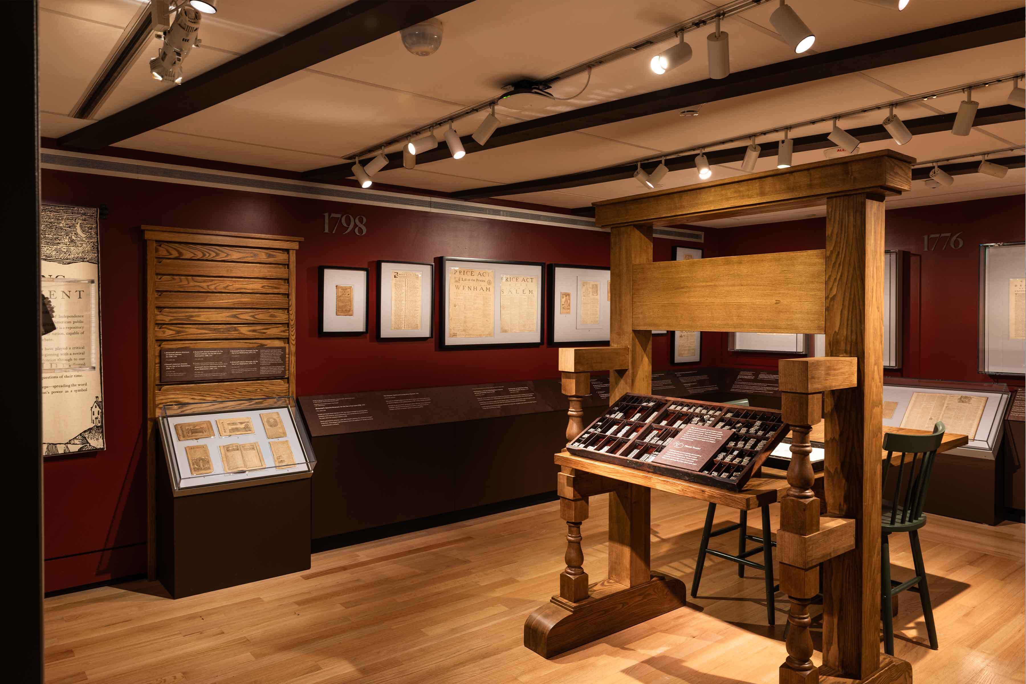The interior of Pressing Importance at PEM, featuring a replica printing bench and several colonial-era documents.