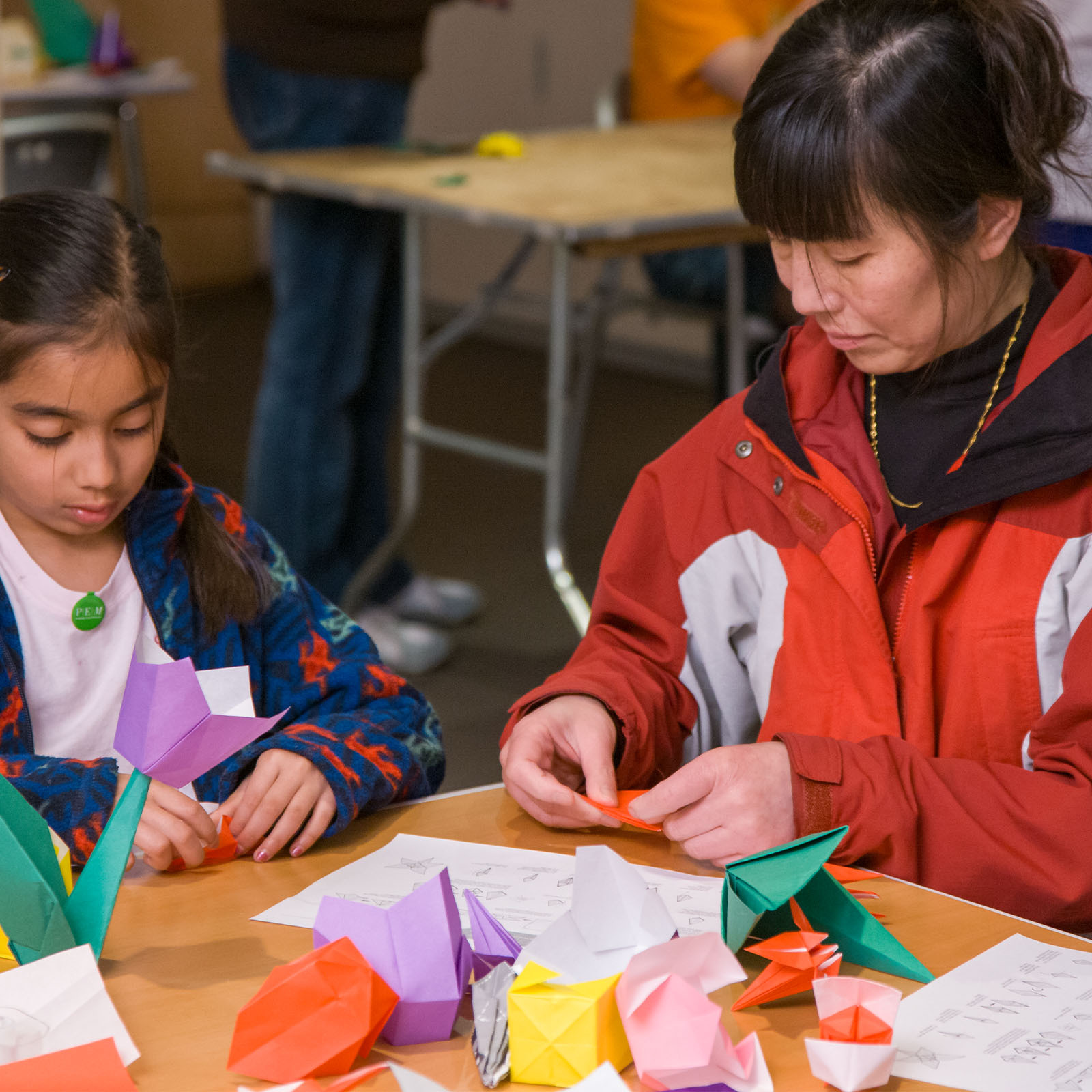 A woman and young girl folding paper at Peabody Essex Museum Origami-making event, 2008