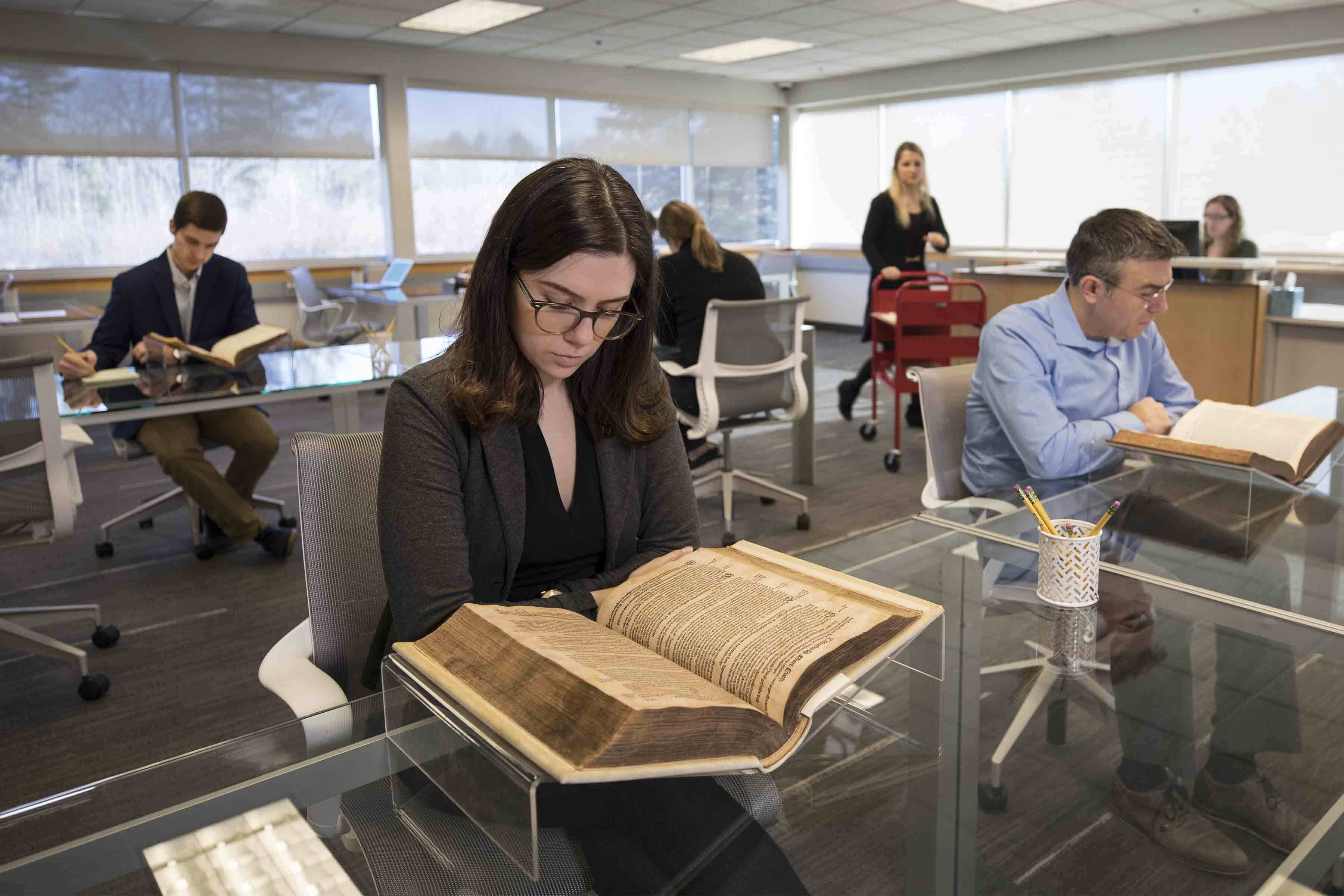 Visitors are sitting at tables reading books in the Phillips Library reading room