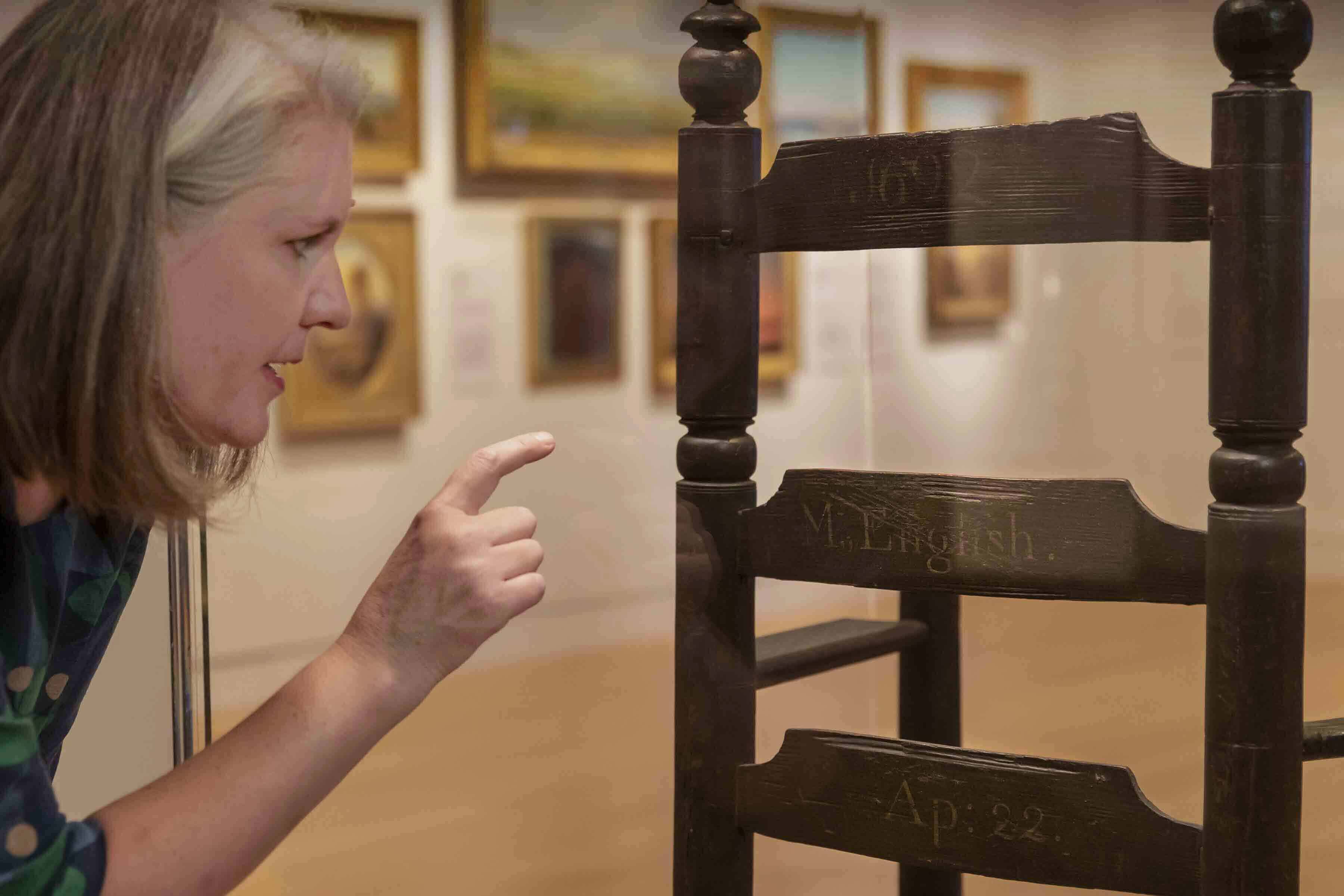 PEM Associate Curator Sarah Chasse points out details on the back of a chair owned by Philip and Mary English who were able to escape the trials and come back to Salem after it was all over. Photo by Kathy Tarantola/PEM