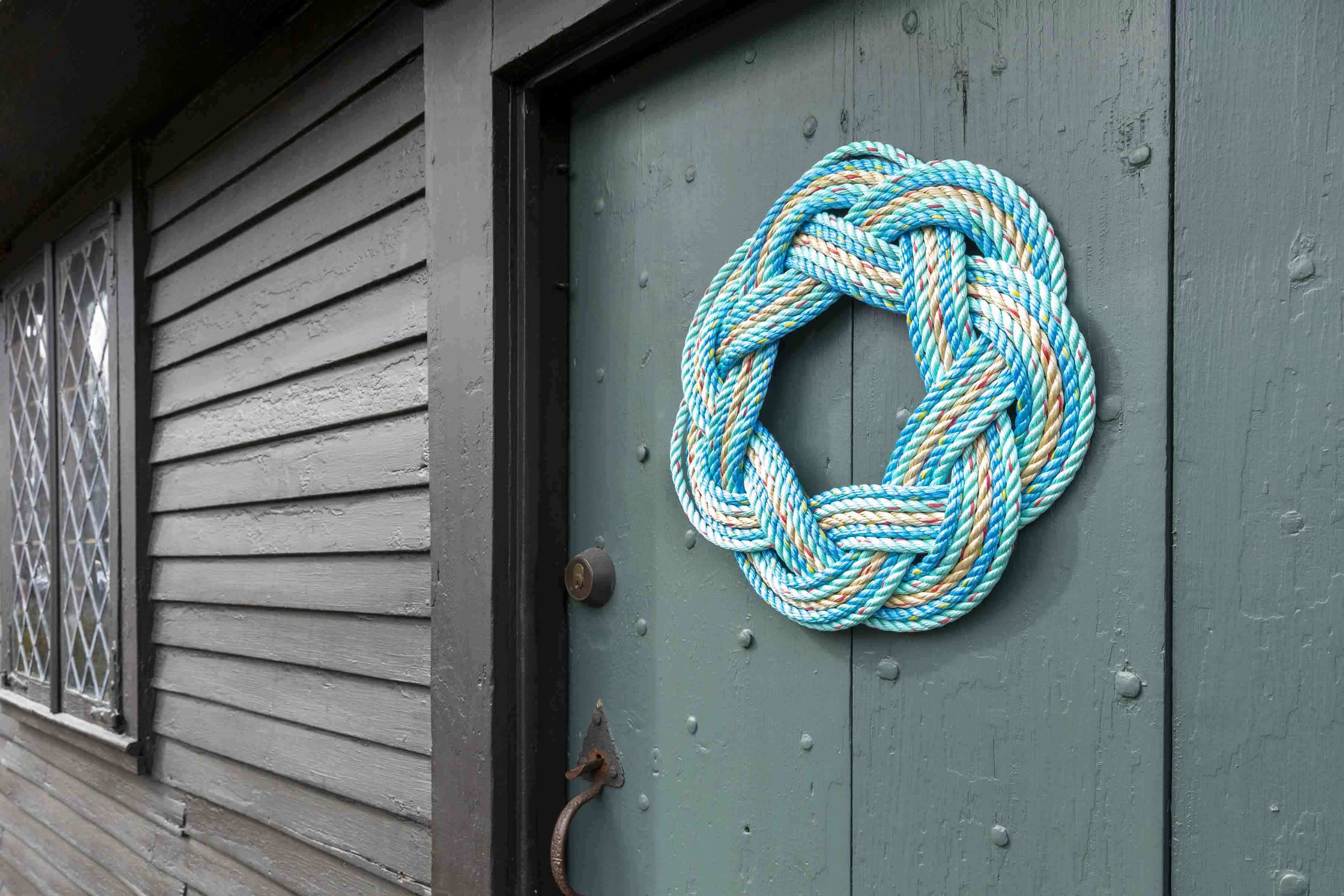 A blue rope wreath on an old brown wooden door