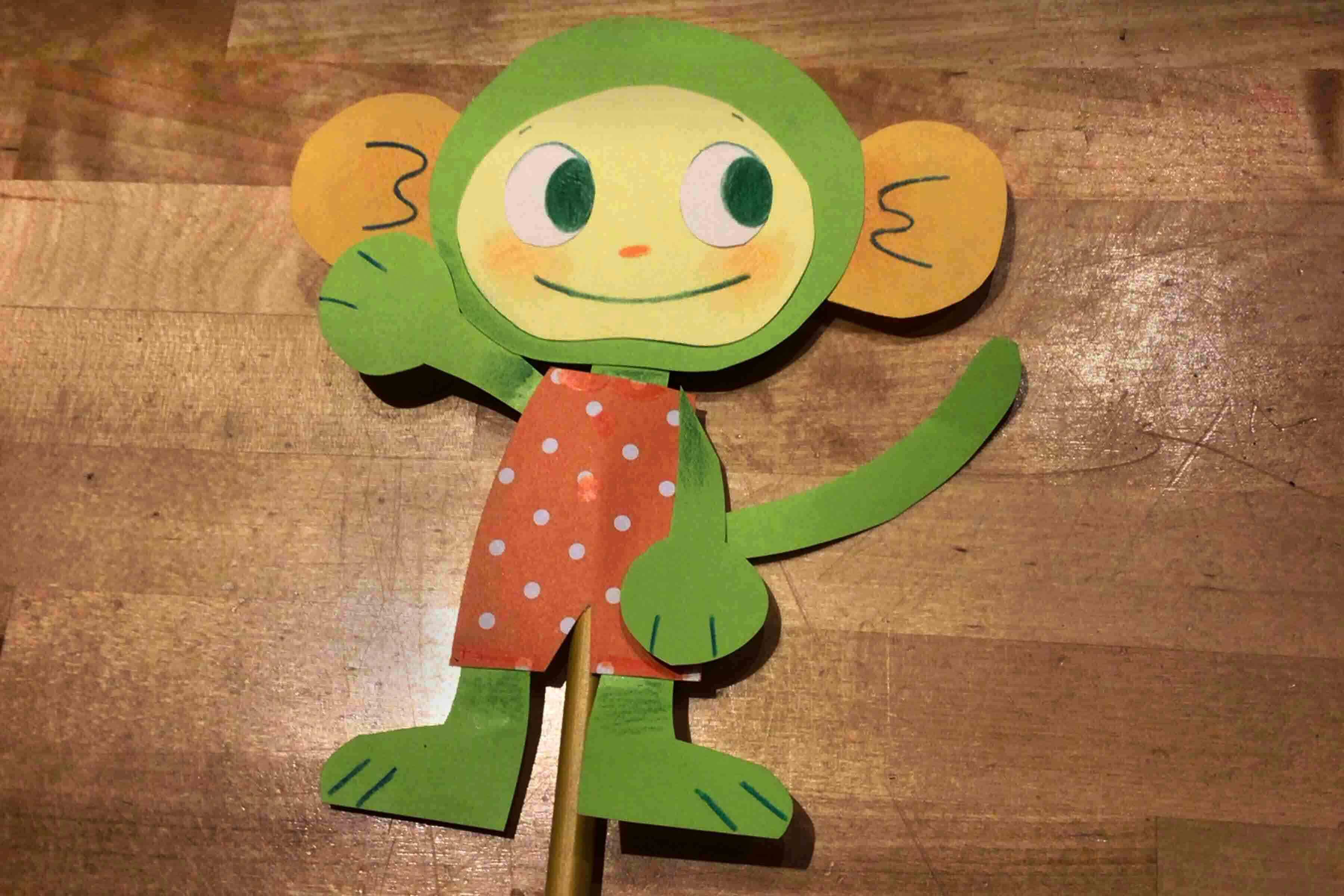 A Collage Characters made out of green cut paper on a wooden background