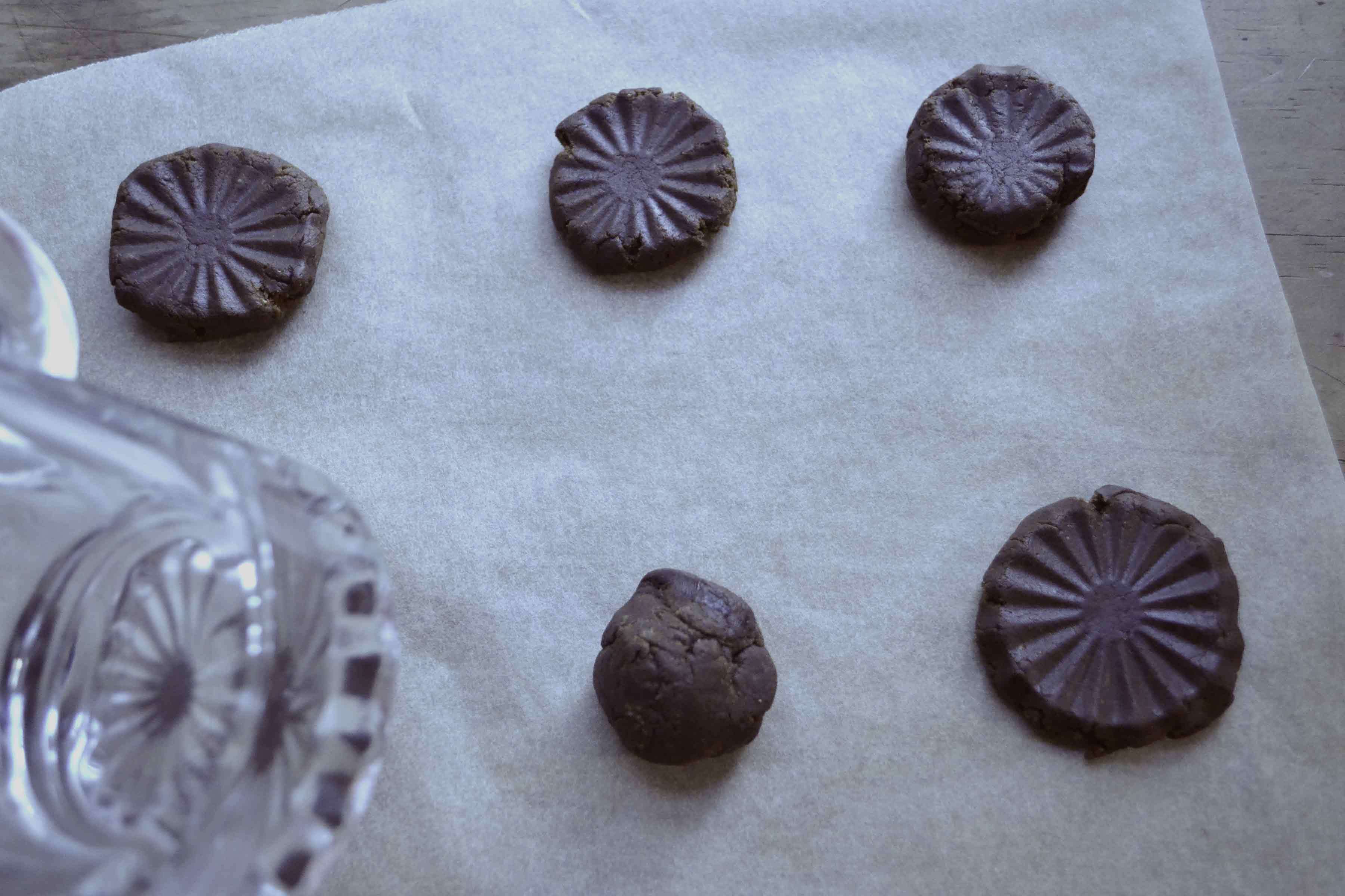 Gingerbread cookie dough pressed into decorative shapes with a drinking glass.
