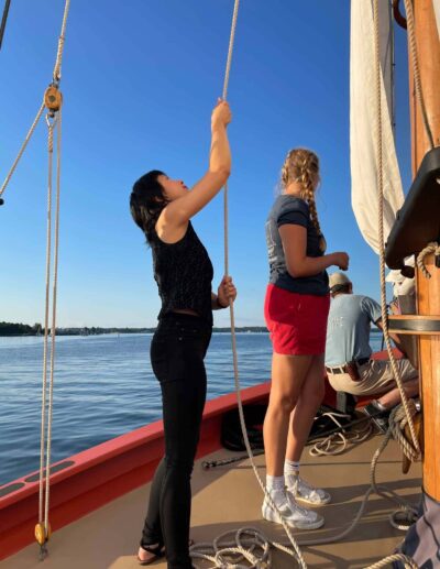 Staff member Melissa Woods helps the crew hoist the sails. Photo by Kathy Tarantola