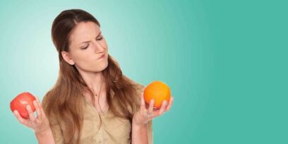 A woman comparing an apple and an orange