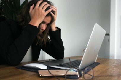 A woman looking at her computer screen and holding her head in frustration