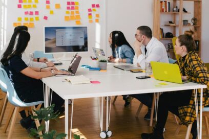 A team of office workers looking at a computer and post it notes in an office