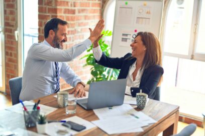 a woman and man high-fiving at desk in office